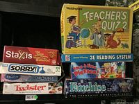 Stack of vintage board games including Teacher's Quiz 2, Staxis, Sorry!, Frozen Trouble, Twister, Face to Face Pie Face, Franchise and 3E Reading System