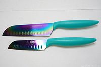 Two Farberware knives with turquoise handles and holographic blades, one larger chef knife and one smaller utility knife