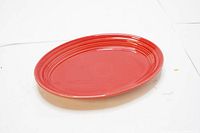 Oval Fiestaware serving plate in scarlett red with visible concentric ring detail design.