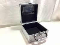 Open view of the small aluminum case showing interior black lining and mirror on lid