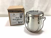 Front view of the new stainless steel brush washer alongside its original cardboard packaging box.