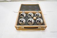 Open wooden case showing six chrome metal Boule balls and one small wooden jack ball inside foam lining.