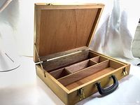 Open view of vintage wooden artist tool box showing interior compartments and fitted lid.
