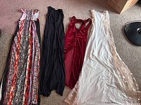 Four women's stretchy dress up dresses laid out on carpet floor including patterned, black, red, and white dresses.