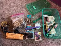 Overview of various hair styling tools and accessories including scissors, clamps, wires, clips, gloves, and combs arranged on carpet and in plastic containers.
