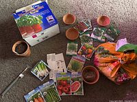 Overview of gardening supplies showing seed packets, small terracotta pots, bag of potting soil, garden hand tool, and seed germination kit