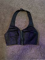 Black leather women's halter crop top laid flat showing full front with zipper and halter strap.