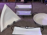 Full view of three serving dishes with black cast-iron stands - white ceramic, including rectangular and triangular shapes.