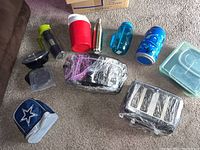 Photo of assorted kitchen items on floor including thermal bottles, crockpot, toaster, Tupperware containers, and insulated lunch bag.