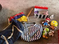 View of several bags including American Eagle bags, a wooden ruler, clear boxes, and plush toys (Mario, Yoshi, emoji character).