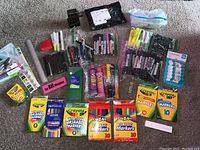 Full view of the various arts and crafts supplies laid out on carpet including markers, crayons, glue sticks, and other items.