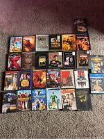 Multiple DVD cases from various movie titles arranged on carpet.