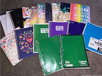 Clear overview of the variety of spiral and composition notebooks included in the lot, showing different colors and designs.