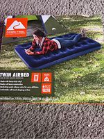 Photo of the boxed Ozark Trail Twin Air Bed showing branded packaging with outdoor camping image and product details like dimensions and weight capacity.