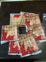 Six individually packaged multi-functional headwear items featuring Canada flag design spread on a dark surface.