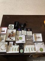 Overview photo of all jewelry items and skincare tubes arranged on table, showing boxes and product packaging.