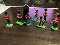 Photo of seven Britain Deetail Queen's Guards soldiers and a black sentry box on a table, showing front and side views in various poses.