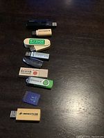 Top view of USB keys and SD card arranged on wooden surface showing various brands and styles.