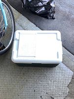 Side view of the closed Coleman cooler placed next to a bicycle.