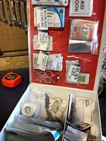 Interior view of first aid kit showing various packaged wound dressings, burn gel, scissors, tape, and medication bottles