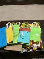 Top view of assorted gift bags in various colors and sizes placed on a table, showing handles and partial fronts