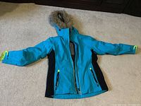 Full view of the blue and black ski jacket with hood laid flat showing front and arms extended.