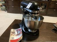 Onyx black KitchenAid Classic stand mixer on tabletop with instruction manual beside it