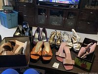 Overview of six pairs of women's dress shoes in different styles and colors laid out on a table, seen with background furniture.