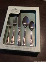 Photo of the boxed set showing the design of the flatware handles and the assortment of forks, knives, and spoons inside the box.
