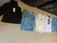 Five women's long sleeve tops laid out on floor, showing color and style variety all with tags.