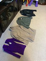 All four items laid out on carpet: two sweaters and two coats; tags visible on sweaters and coats.