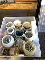 Full view of plastic container holding assorted screws, bolts, nuts, and plastic wall anchors in jars and small boxes.