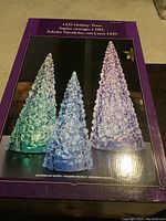 Box with image of three glitter holiday trees with blue, green and purple color changing LED lights showing large, medium and small sizes