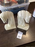 Pair of hand-carved onyx Trojan horse head bookends shown from the front angle on a wooden surface.