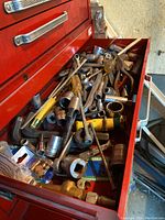 Top drawer filled with assorted hand tools including socket wrenches, ratchets, extension bars, sockets, screwdrivers, pliers, wire, and other tools.