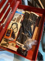 Top view of the first drawer showing digital meter, black protective sleeves, hardware in packages, and miscellaneous small tools