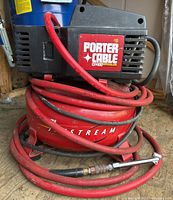 Porter Cable CF1400 air compressor showing the motor and coiled red hose on top.