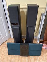 Two Sony floorstanding speakers placed behind and one Bang & Olufsen BeoSound 2000 unit in front