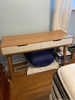 Front view of the Canvas Oslo console desk showing wood tone body and white drawer fronts with cut-out handles.