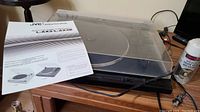 Turntable with instruction manual laid out on a wooden surface, showing model details and brand JVC