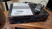 JVC stereo integrated amplifier with remote and instruction manual on a wooden table.