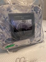 Photo of the comforter set still sealed in original clear plastic packaging, showing Adrienne Vittadini brand and product label.