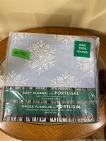 Packaged king size soft flannel sheet set showing blue fabric with snowflake patterns and product labeling indicating 100% cotton luxury weight bedding from Portugal.
