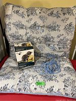 Photo showing Andrina pet bed with blue and white floral design, electronic mouse toy box, and blue leash on the bed