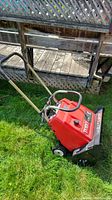 Side view of red Toro CR-20E snow thrower showing handle and wheels on grass.