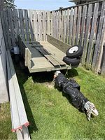 Overview of trailer showing wood deck, metal frame, removable side walls and spare tires leaning on deck