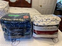 Two king size sheet sets side by side in clear packaging showing plaid and floral designs.