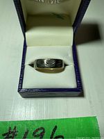 Front view of ring in box showing white gold center with engraved pattern