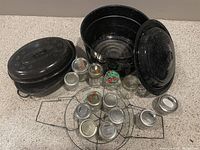 Display of entire lot showing black speckled roasting pan with lid, canner pot with lid, canning jar rack and assorted jars in front.