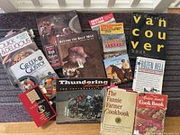 Collection of mainly cookbooks and western-themed books arranged on a purple carpet